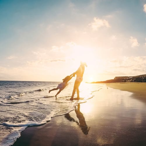 Mother and daughter having fun on tropical beach - Mum playing with her kid in holiday vacation next to the ocean - Family lifestyle and love concept - Focus on silhouettes